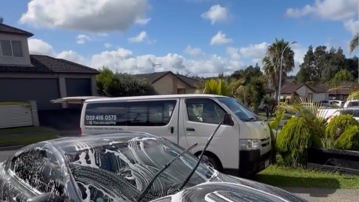 Titan Auto Detailing van parked at an Auckland house while a black car is covered in snow foam on the driveway